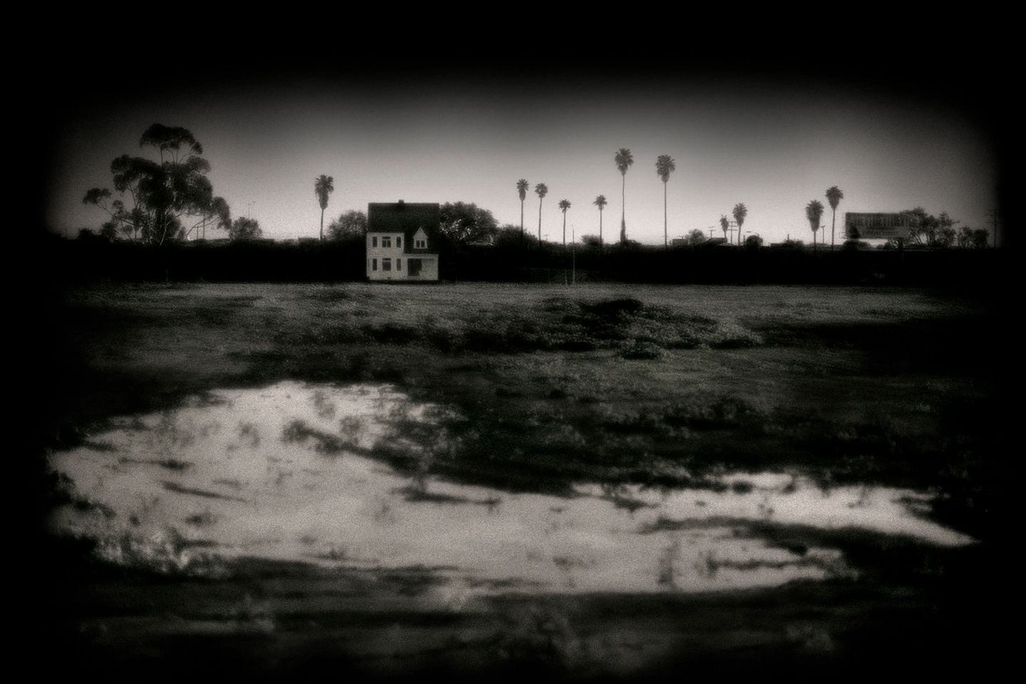 A black and white photo of a house in the middle of nowhere.
