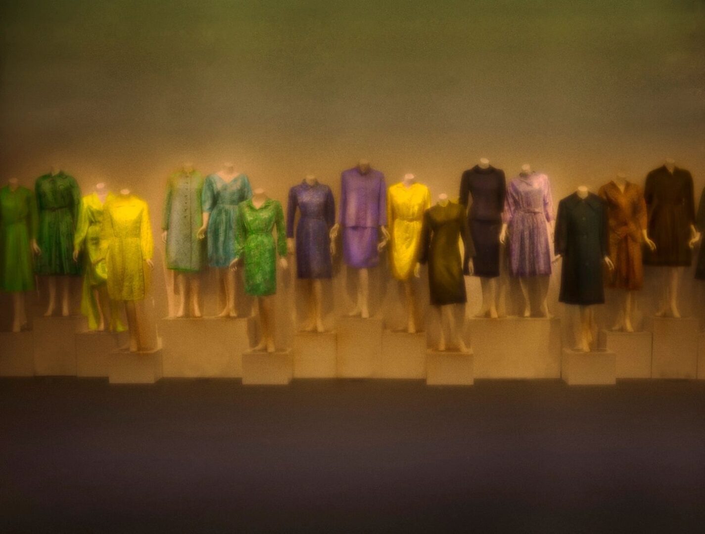 A row of dresses are lined up on the wall.