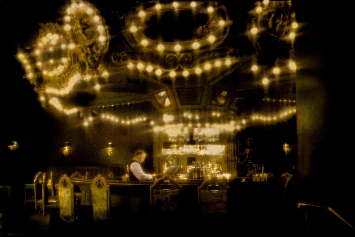 A man sitting at the bar in front of lights.