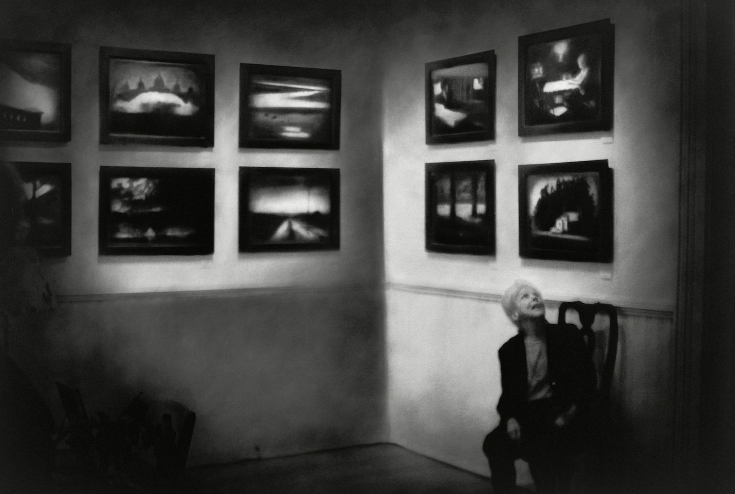 A man sitting in front of several paintings.