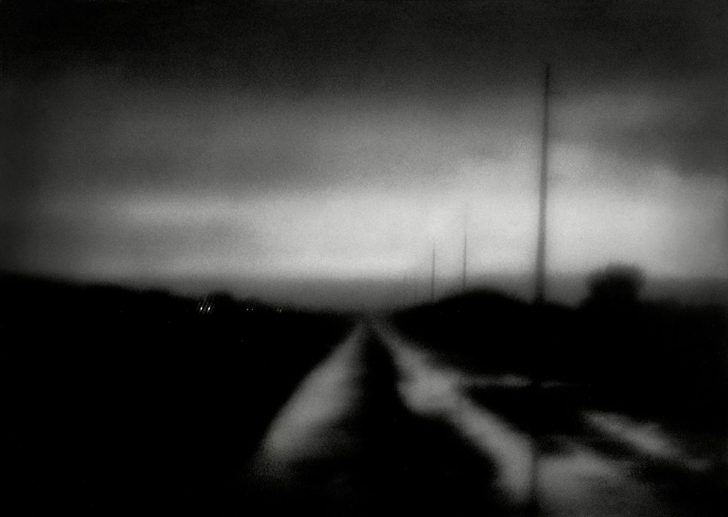 A blurry photo of an empty road with power lines in the background.