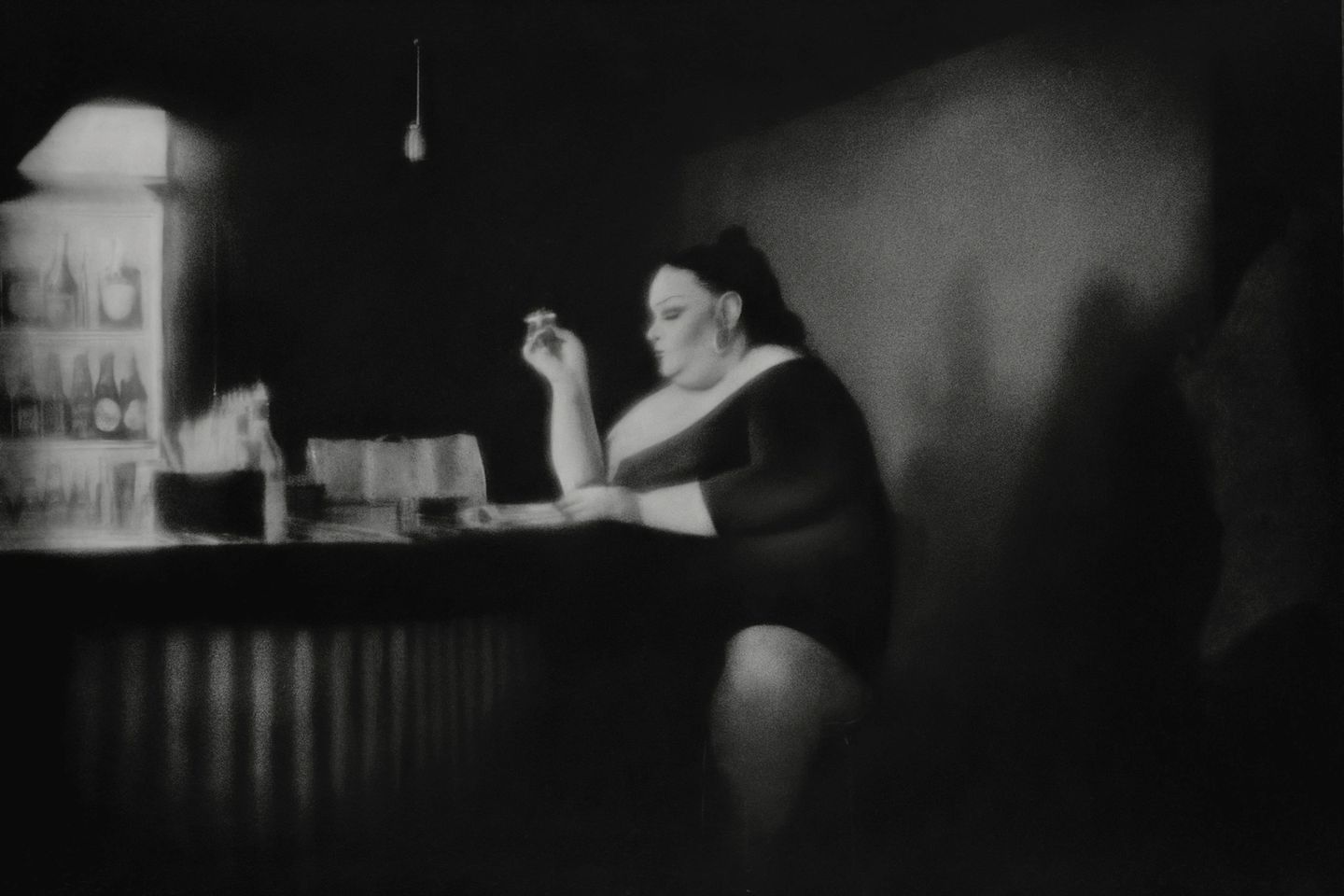 A woman sitting at the bar with her hand on her chin.
