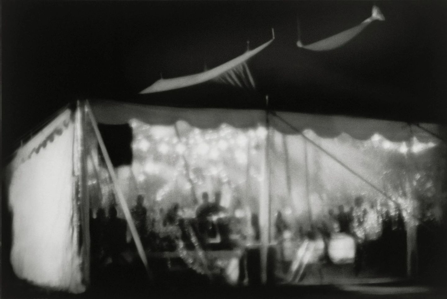 A black and white photo of people in an open tent.